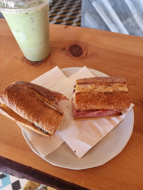 photo of ham sandwich cut in half with bite taken out of it