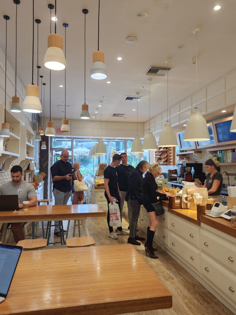 Interior of Rosetta in Miami. Buff man on laptop at a table. Patrons in line.